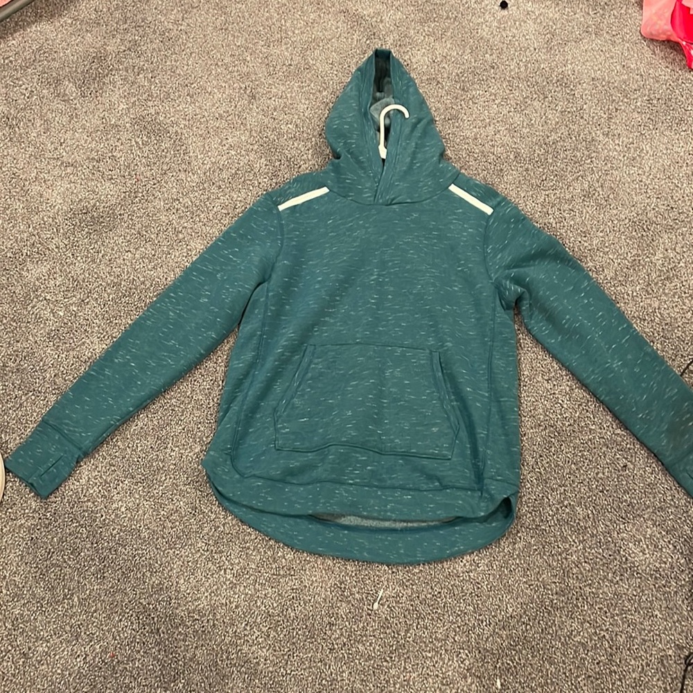 A greenish blue large sweatshirt with some white patterns.